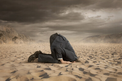 Business-Person steckt den Kopf in den Sand