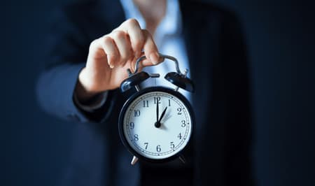 Person im Anzug hält eine Uhr