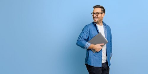 Unternehmer mit Laptop lacht in seine berufliche Zukunft